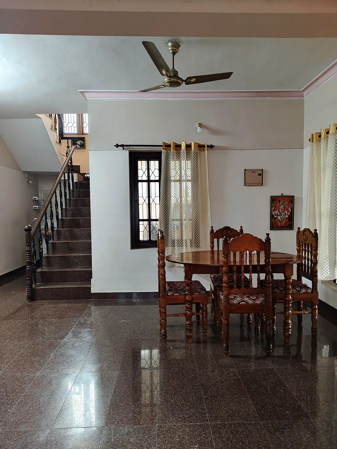 Round wooden dining table and chairs beside the staircase