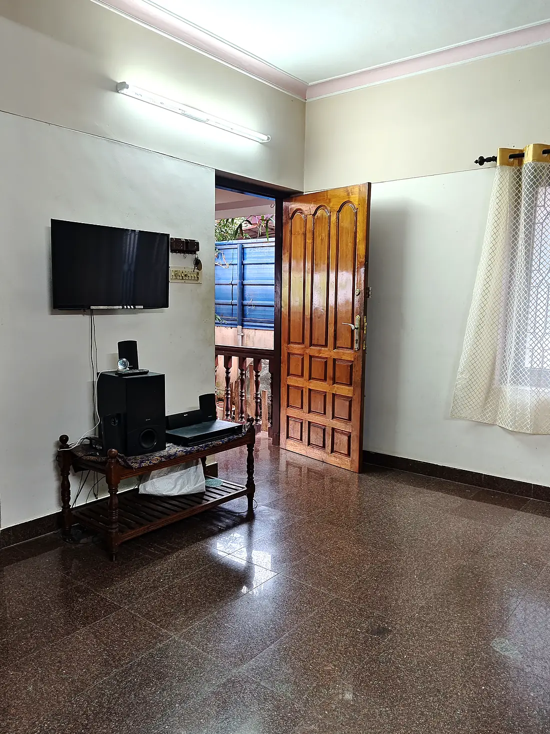 Living room with a wall-mounted television and the front door open onto the verandah